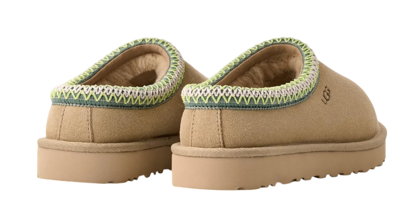 Pair of tan slippers with green trim on a white background